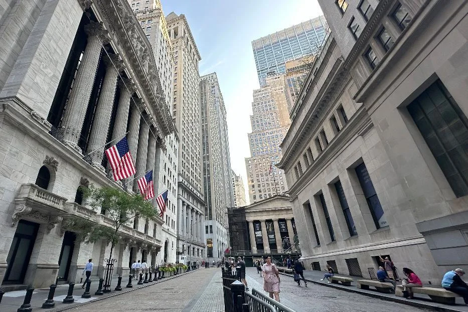 Wall Street with the New York Stock Exchange flags on the left and Federal Hall at the end of the street